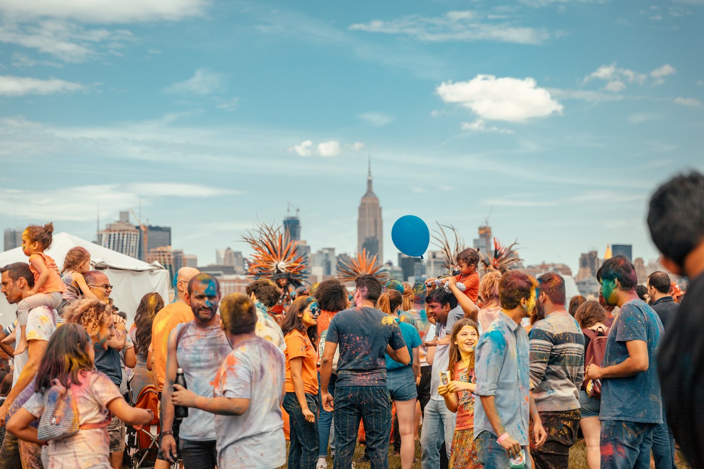 People covered in colored powder celebrate at an outdoor festival.
