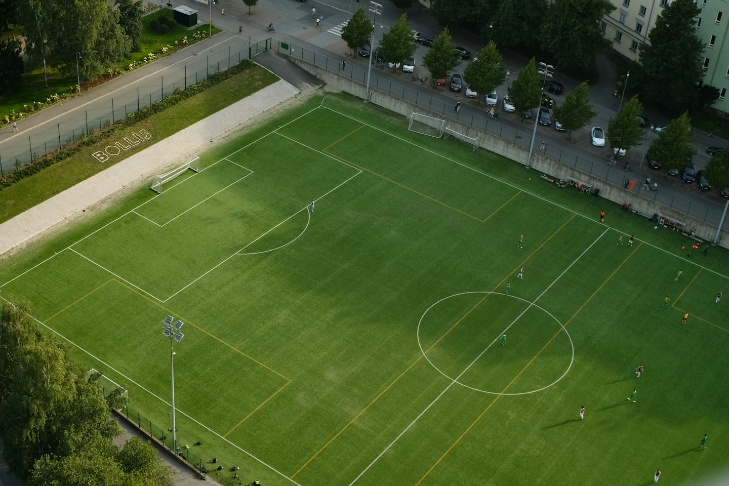 Soccer players on a bright green field with goals.